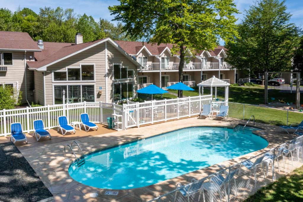 einen Pool mit Stühlen und Sonnenschirmen vor einem Haus in der Unterkunft Somerset Inn & Suites in Ephraim