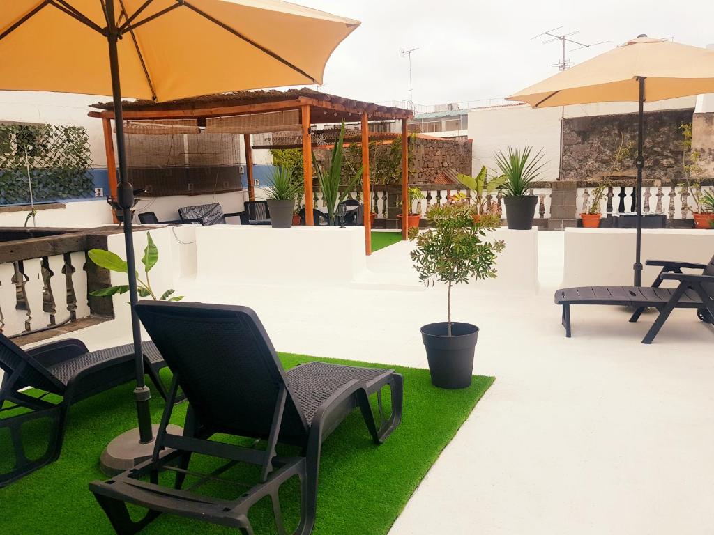 a patio with chairs and umbrellas and grass at Casa La Dama de Arucas in Arucas