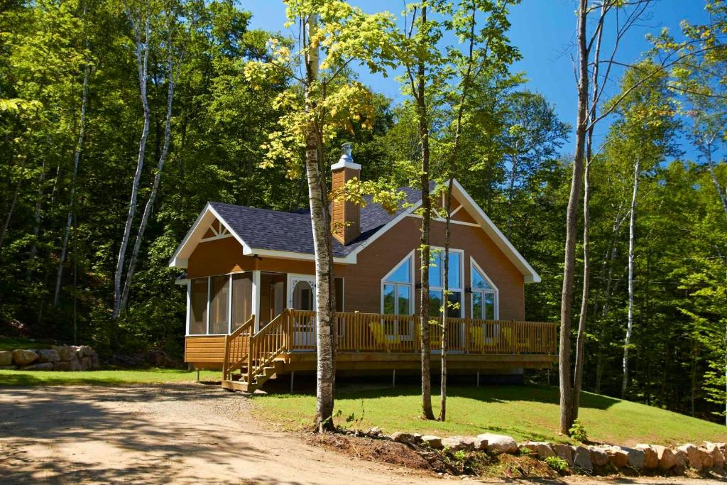 a house with a large porch in the woods at Chalets Lanaudière in Rawdon