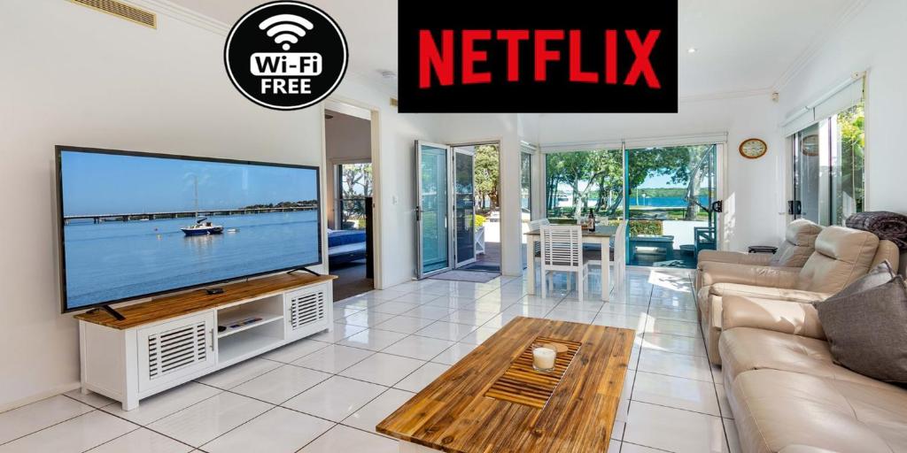 uma sala de estar com uma televisão, um sofá e uma mesa em Keith's on Sylvan Beach, 1 of the 4 most popular units on Bribie em Bellara
