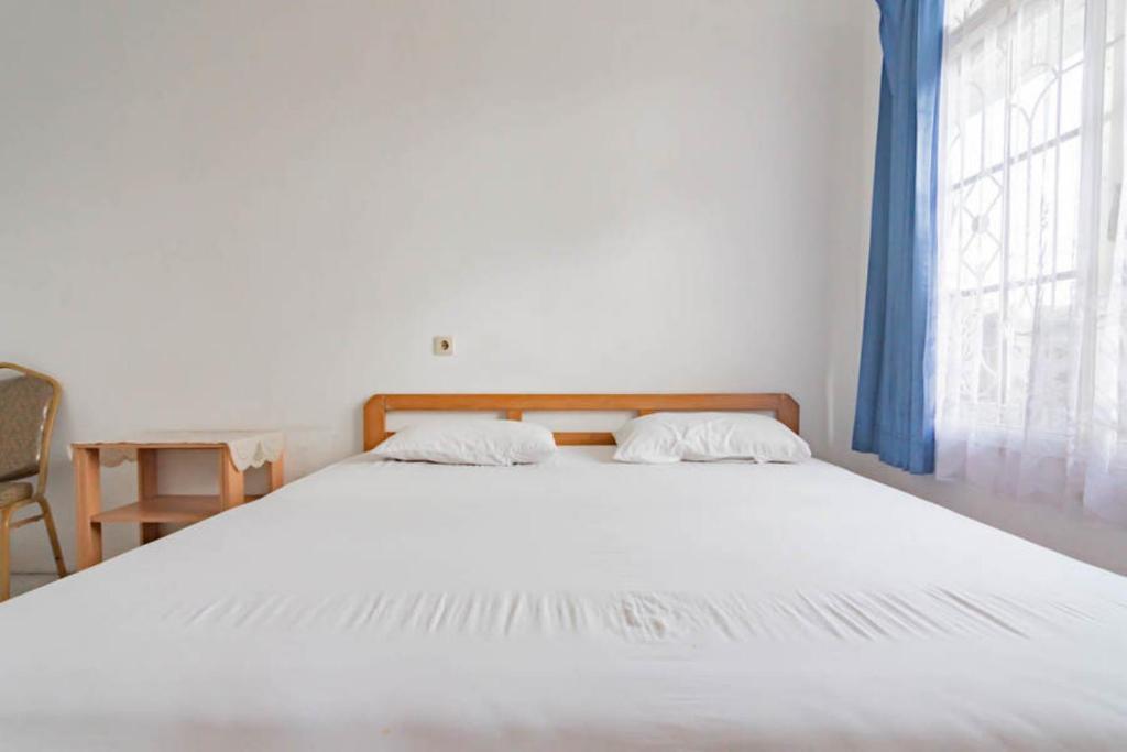 Un dormitorio con dos camas y una ventana. en Pall Inn Puncak Mitra RedDoorz, en Bogor