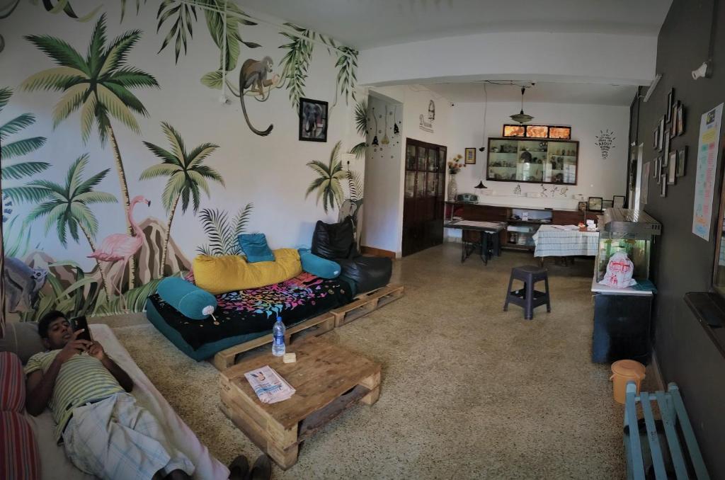 una sala de estar con palmeras en la pared en Monkey Mind Hostel, en Margao