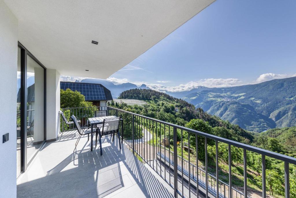 balcón con mesa, sillas y montañas en Thalerhof Naturae Montes Ritten en Collalbo