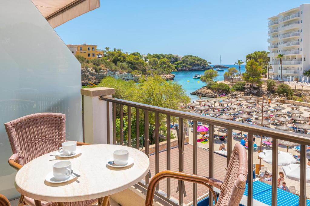 een balkon met een tafel en stoelen en uitzicht op het strand bij Apartamentos Playa Marina in Cala Ferrera