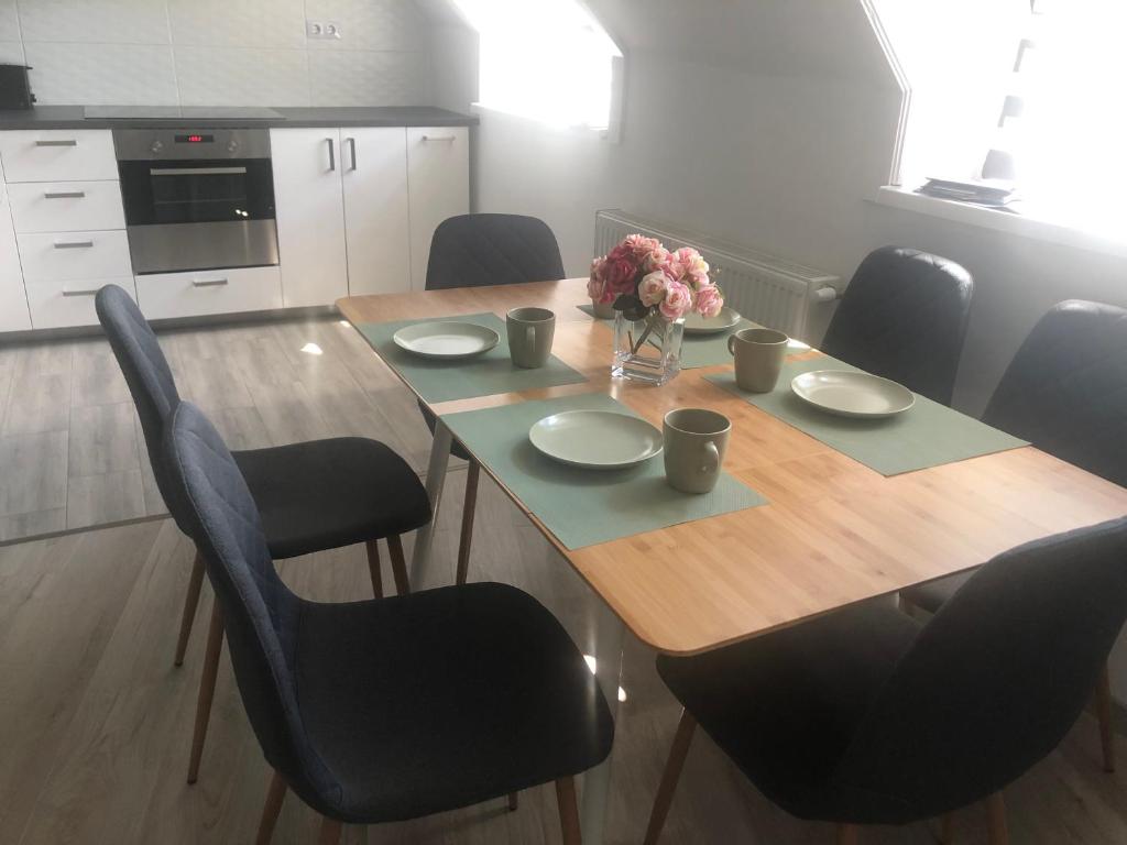 a dining room table with chairs and a wooden table with flowers at Sára magánszálláshely Debrecen in Debrecen