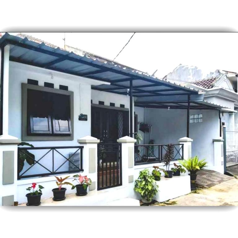 uma casa com um telhado azul e vasos de plantas em Situ Gede Indah HOMESTAY em Tasikmalaya