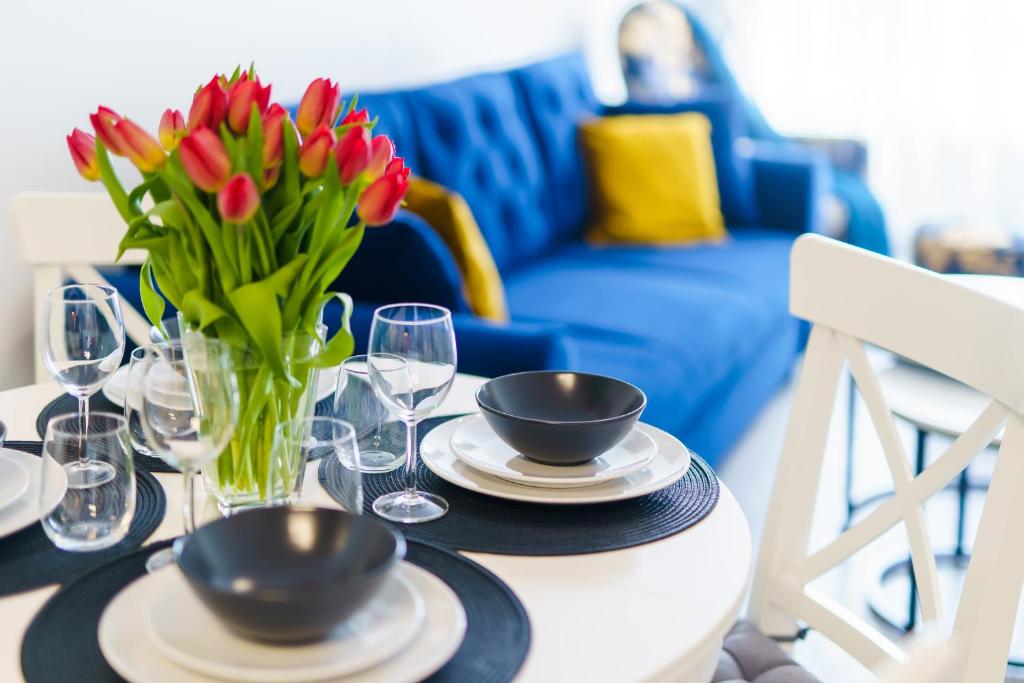 a table with a vase of red tulips on it at Apartamenty Adyl Platany in Kołobrzeg