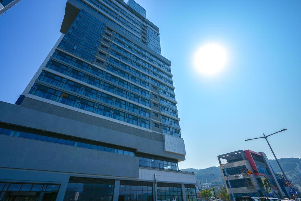 un edificio alto con el sol en el cielo en Shiftdoor Residence Hari en Busan