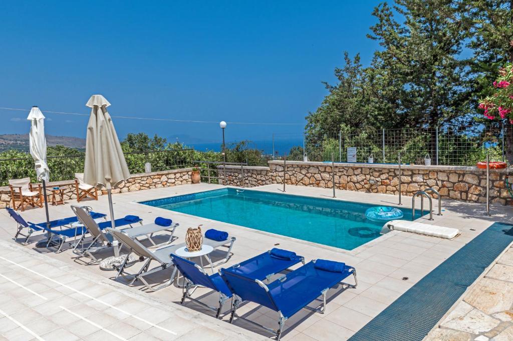 a swimming pool with chairs and a table and an umbrella at Villa Despina in Prinés