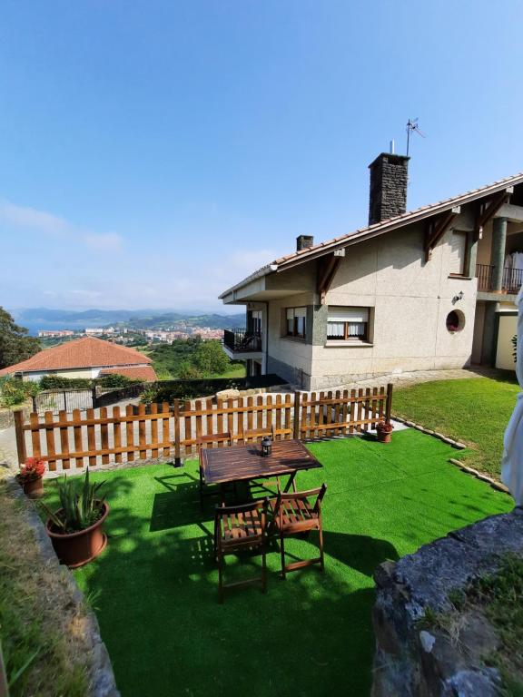 een patio met een tafel en stoelen op het gras bij Gibeleburu in Bermeo