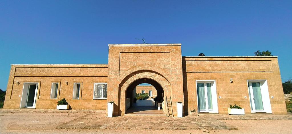 un bâtiment en briques avec une arche en face de celui-ci dans l'établissement Residenza Case Arse, à Torre Lapillo