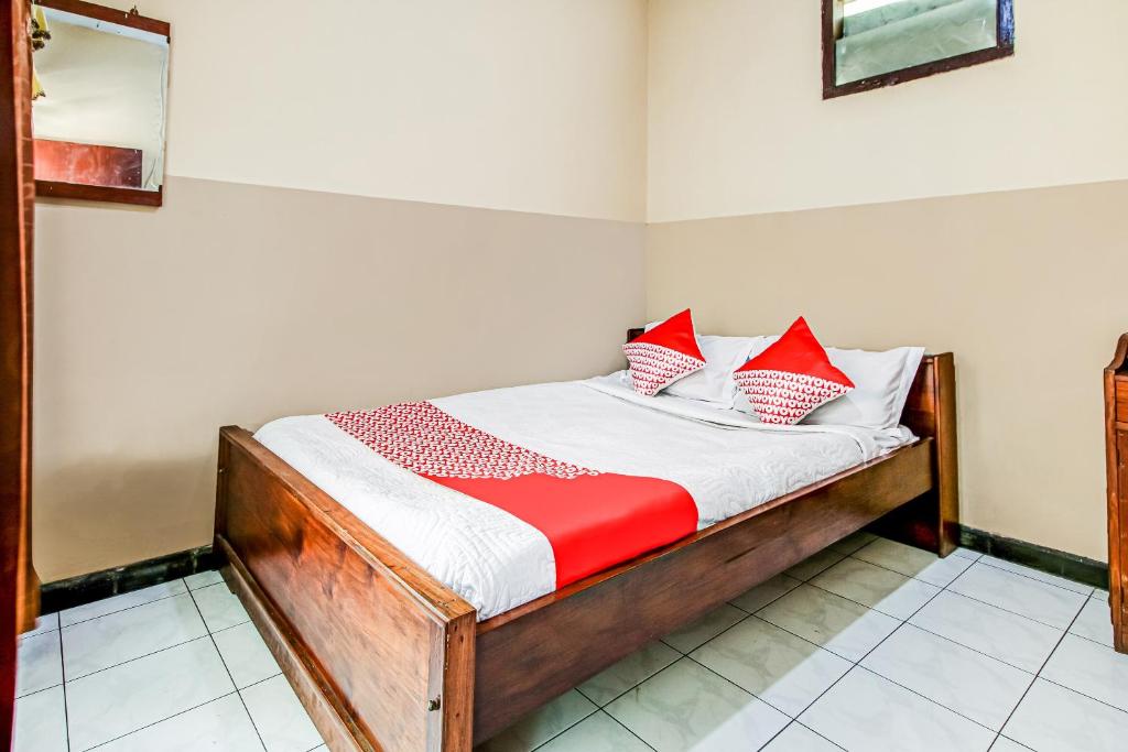 Una cama pequeña con almohadas rojas y blancas. en OYO 91053 Desa Wisata Gilimanuk en Gilimanuk