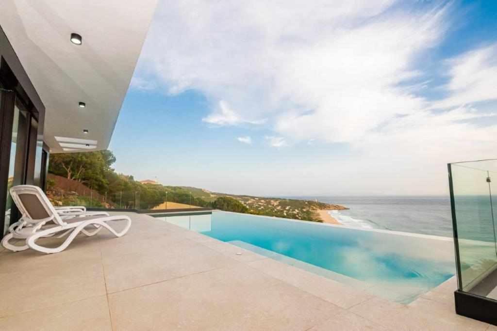 a white chair sitting on a balcony overlooking the ocean at Villa El Buzo in Zahara de los Atunes