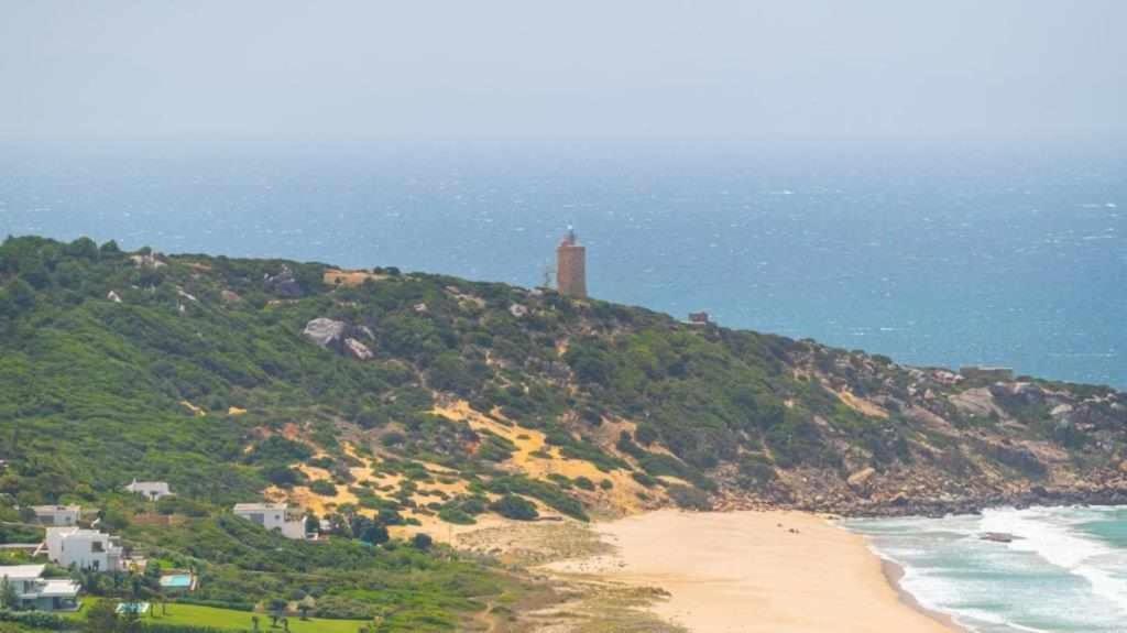 a lighthouse on top of a hill next to the ocean at Villa El Buzo in Zahara de los Atunes