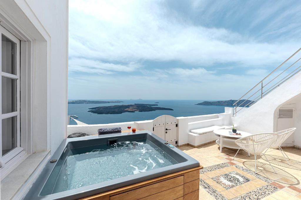 a hot tub on a balcony with a view of the ocean at Calderas Hug & Panoramic Sea View - 3 Lux Suites in Imerovigli