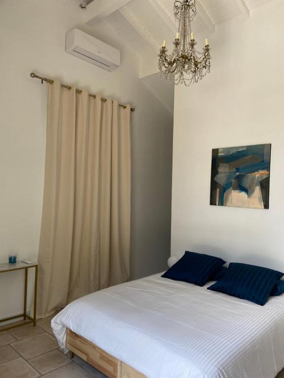a bedroom with a bed with blue pillows and a chandelier at Mas de charme Jas de Berrias piscine proche Les Vans Ruoms Gorges Ardèche in Berrias Et Casteljau