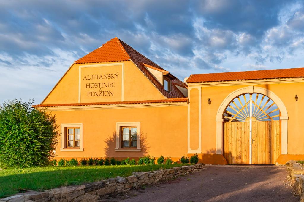 Una iglesia naranja con un cartel en el costado. en Althanský hostinec, en Znojmo