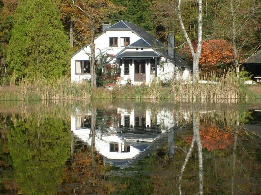a house is reflected in a body of water at PROPRIETE BORDEE D'ETANGS, PROPICE A LA DETENTE in Florenville