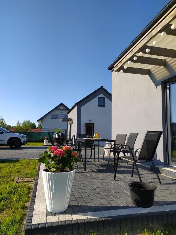 a patio with chairs and a table with flowers at Zagajka SUN in Sarbinowo