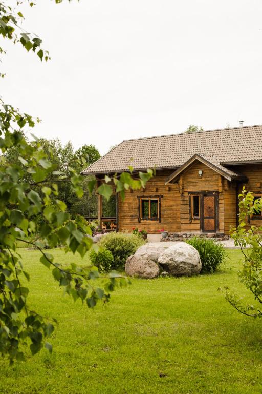 a log house with a yard in front of it at Vila Juodenėnai in Žaugėdai