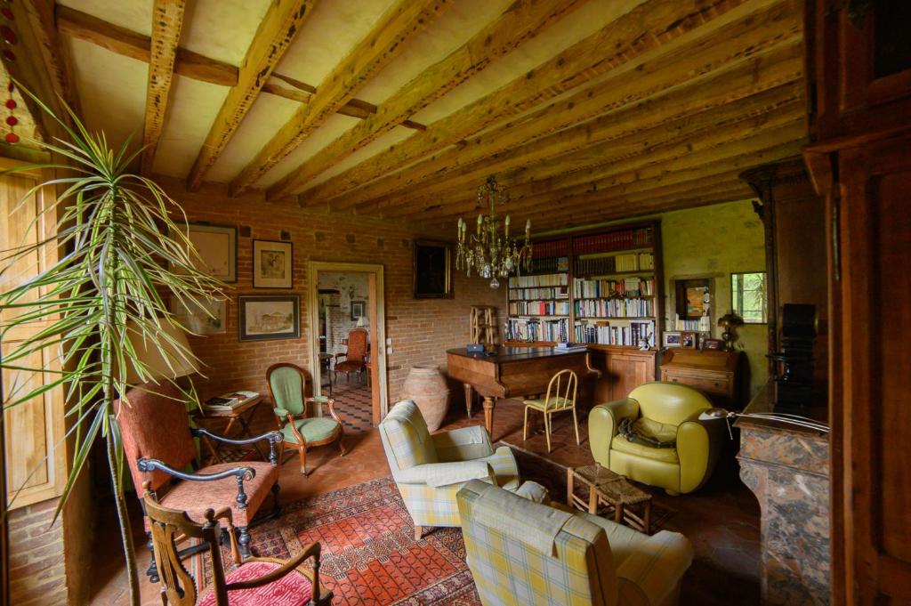 a living room filled with furniture and a wooden ceiling at Chambre d'Hôtes La Ferme du Pré-Martin in La Génevraie