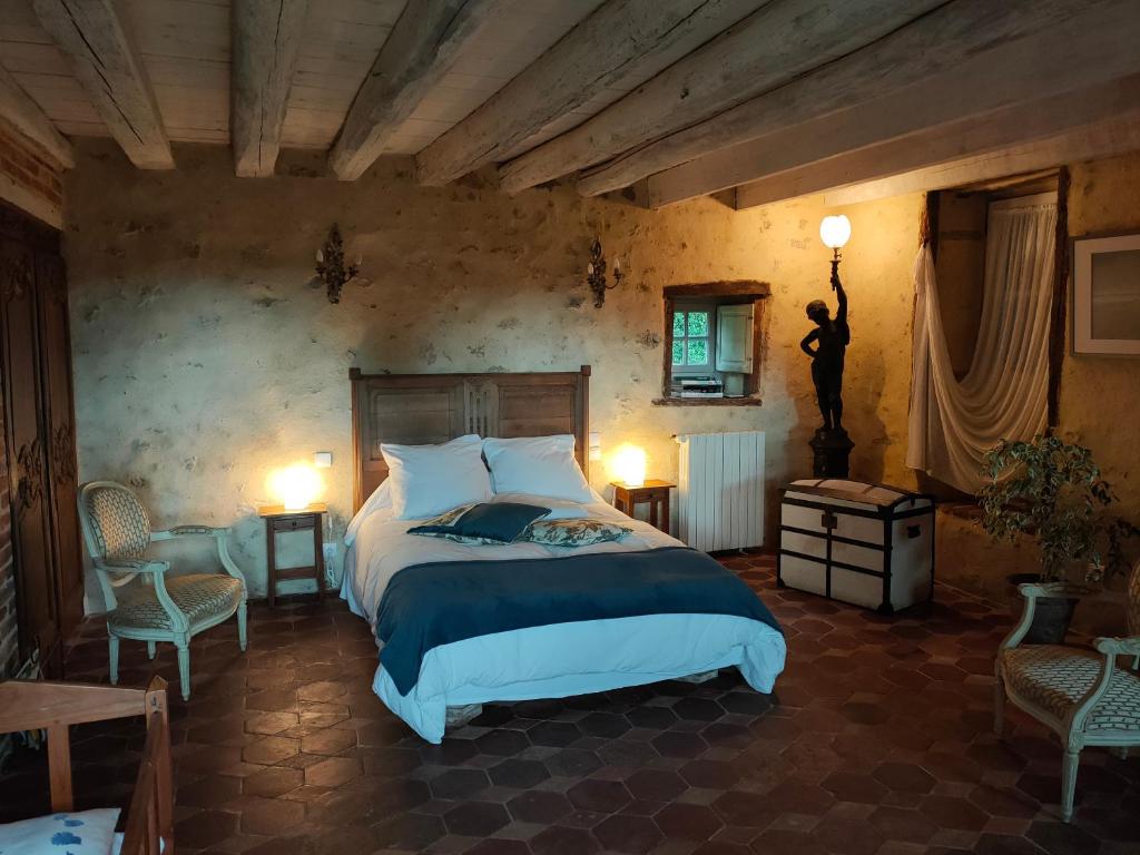 - une chambre avec un grand lit et deux chaises dans l'établissement Chambre d'Hôtes La Ferme du Pré-Martin, à La Génevraie