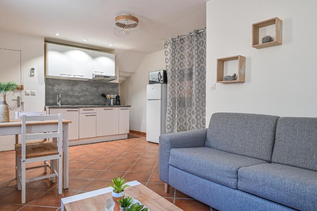 a living room with a blue couch and a kitchen at Super studio climatisé in La Ciotat