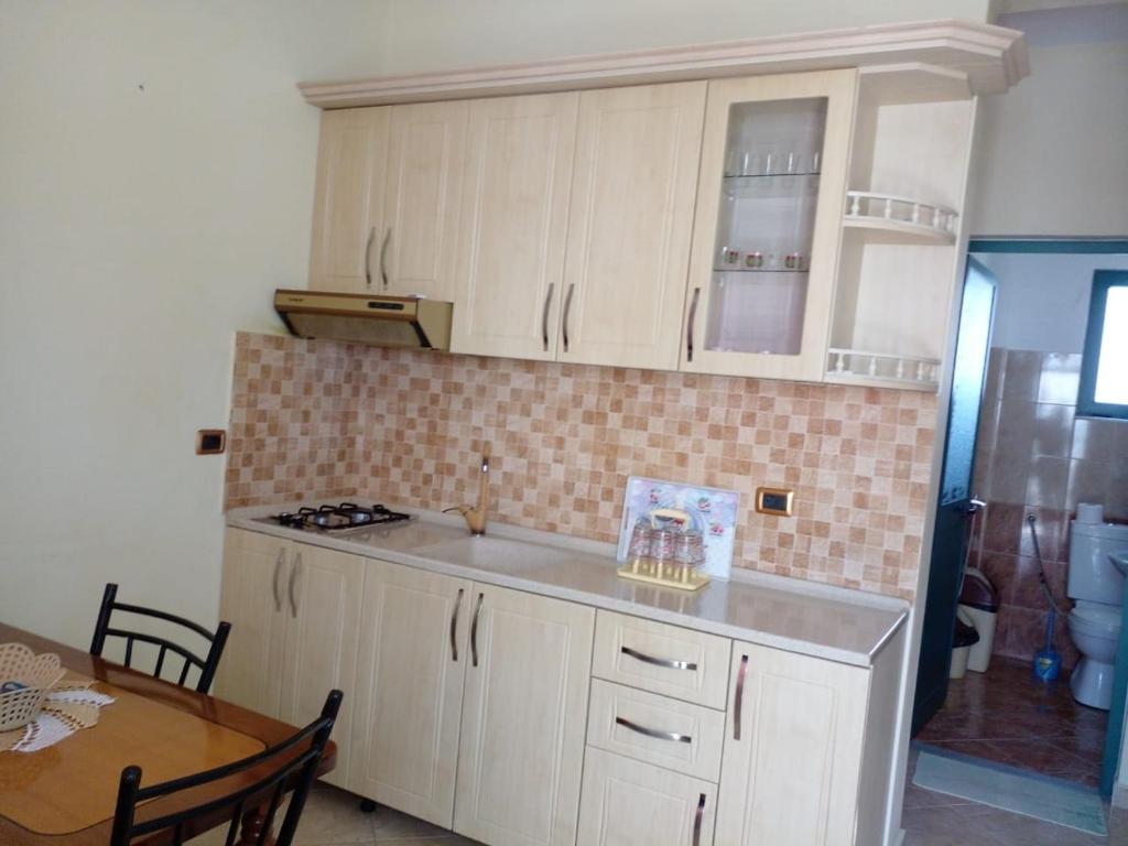 a kitchen with white cabinets and a table and a dining room at DRINI in Velipojë