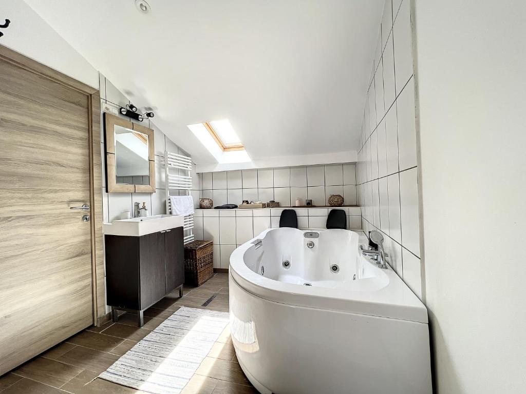 baño con bañera blanca grande y lavamanos en Maison de ville jacuzzi wiffi à 4km aéroport Charleroi, en Charleroi