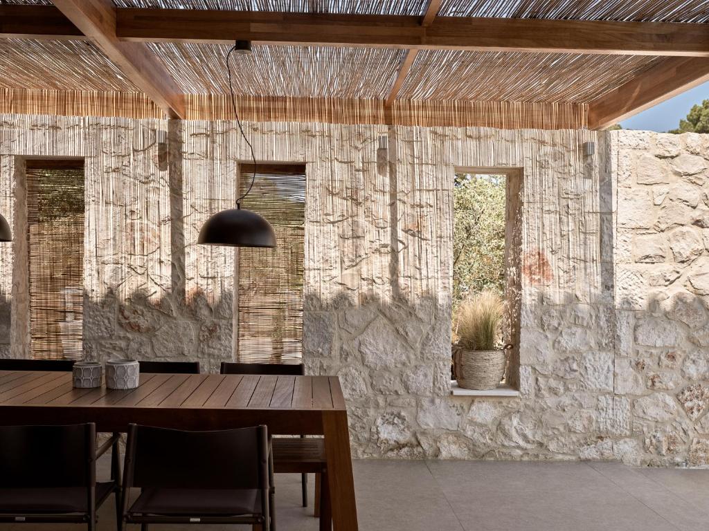 jadalnia ze stołem i kamienną ścianą w obiekcie Cielo villas - An Authentic Mediterranean Living w mieście Zakintos