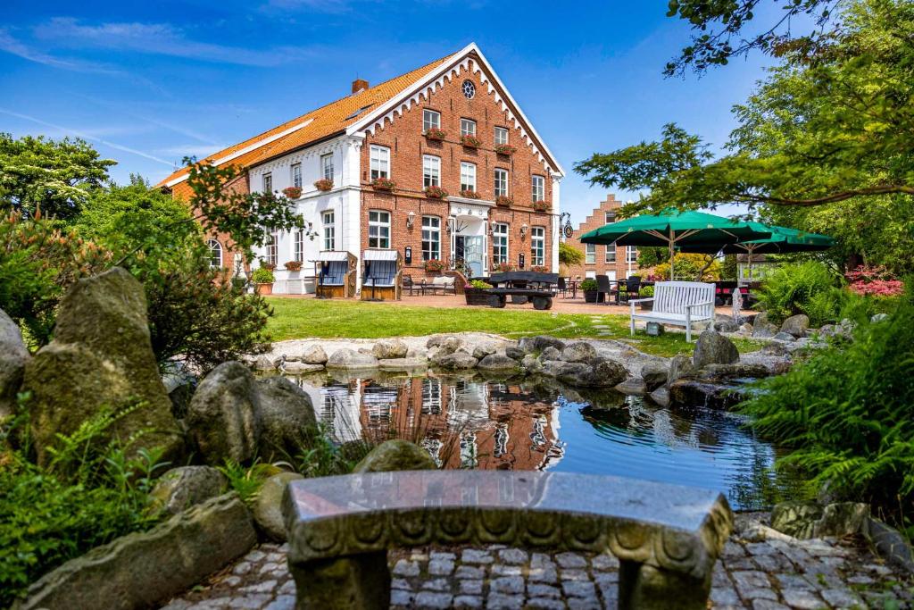 un bâtiment et un étang en face d'un bâtiment dans l'établissement Hotel Landhaus Steinfeld, à Greetsiel