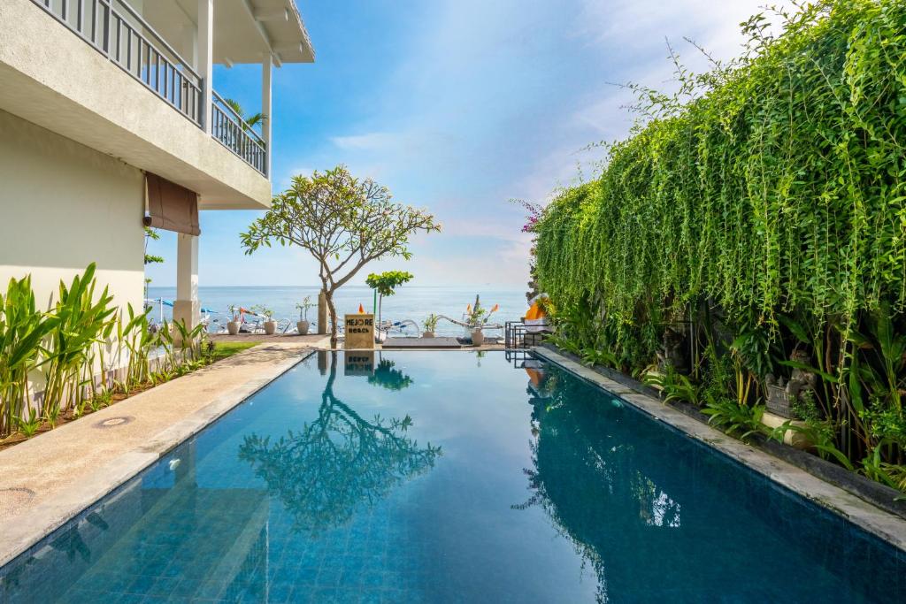 uma piscina de beiral infinito numa villa com o oceano ao fundo em Mejore Beach Hotel em Amed