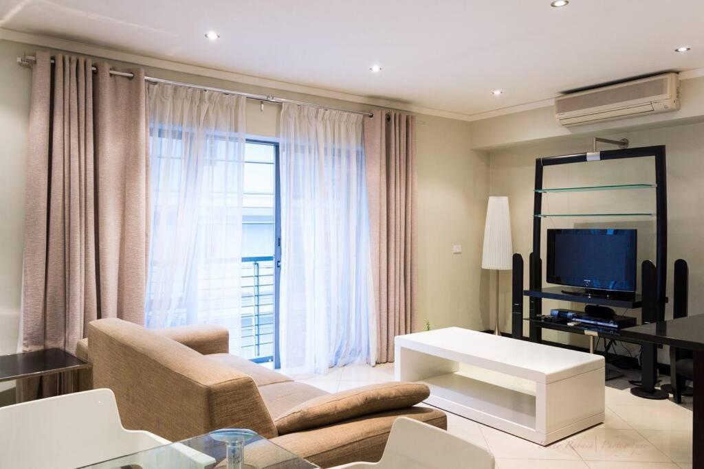 a living room with a couch and a tv at Icon Luxury Apartments - Central Cape Town in Cape Town