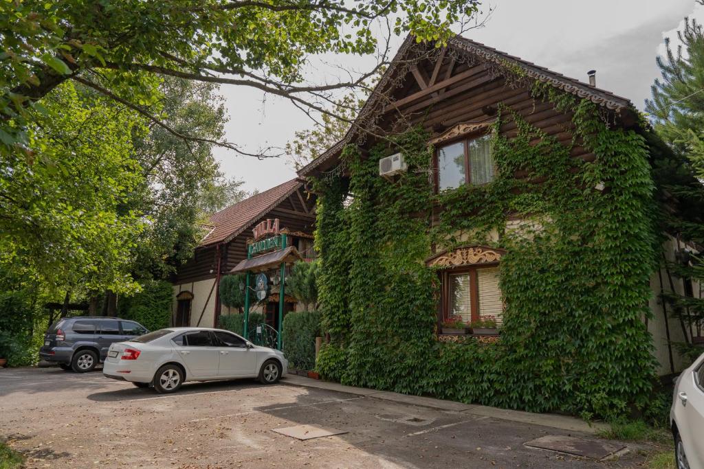 ein Auto, das vor einem mit Efeu bedeckten Haus parkt in der Unterkunft Villa Garden Hotel in Solotschyn