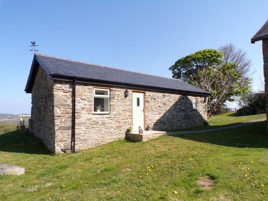una pequeña casa de ladrillo con una puerta blanca en un campo en Detached barn with valley views near Cardigan, en Cardigan