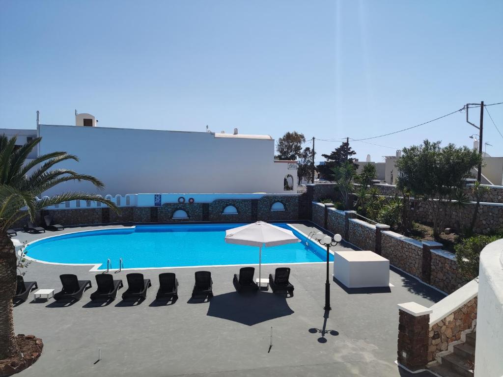 a swimming pool with chairs and an umbrella at Albatros Hotel in Karterados