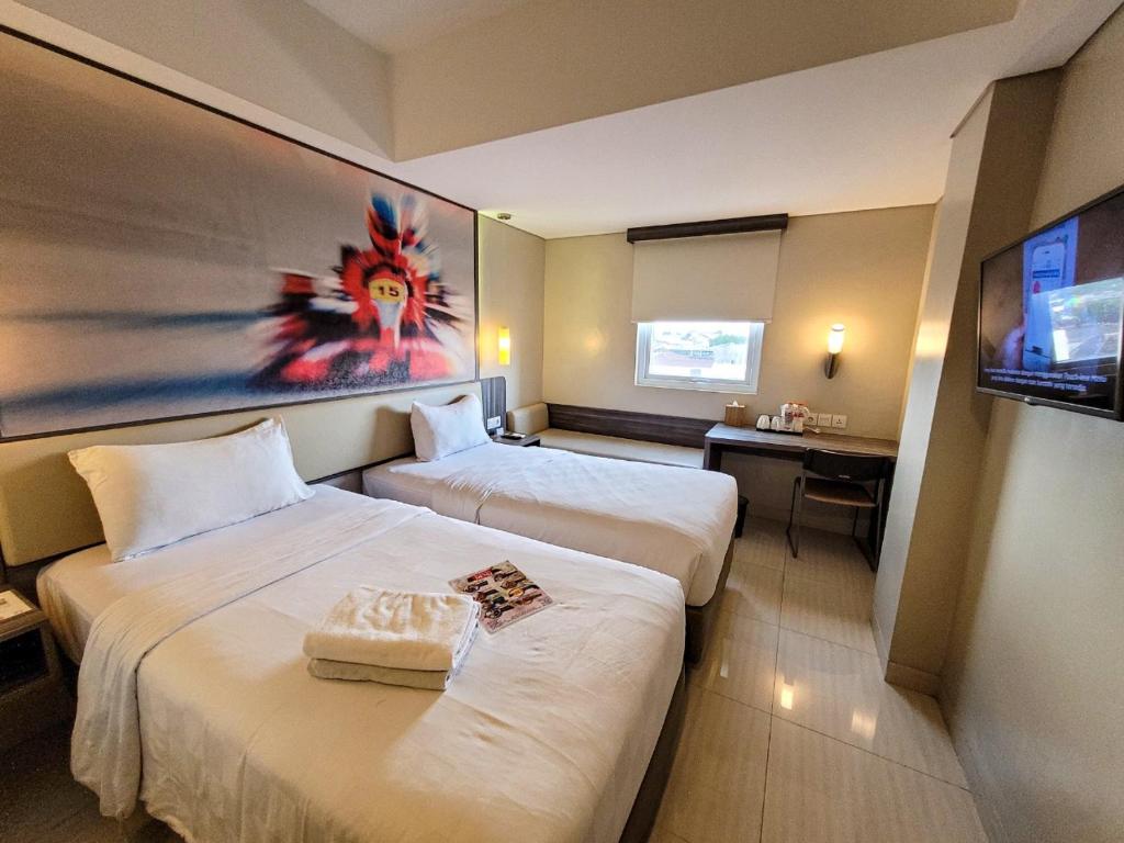 Habitación de hotel con 2 camas y TV de pantalla plana. en Cordela Kartika Dewi Yogyakarta en Yogyakarta