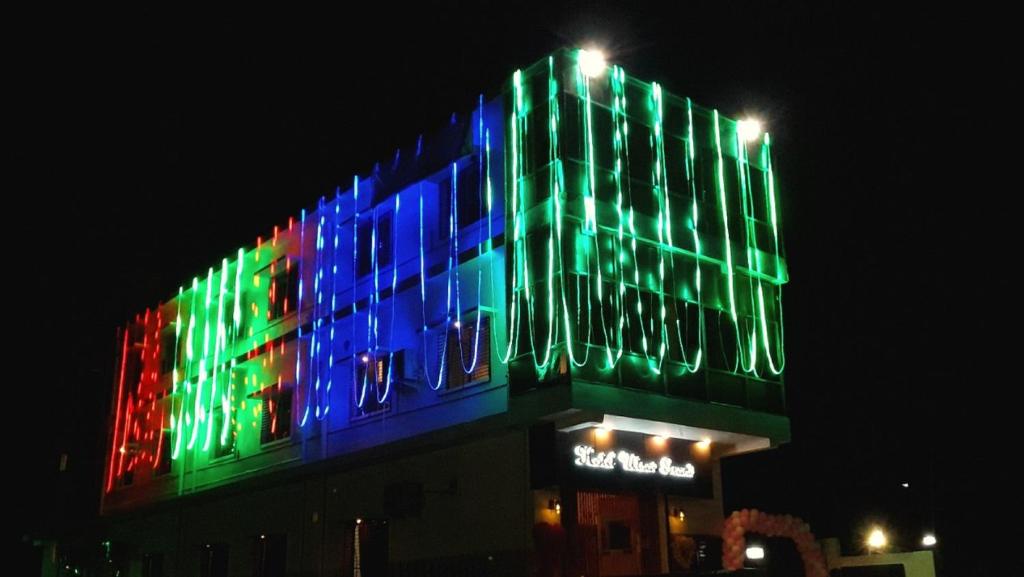 un edificio con luces de colores por la noche en Utsav Grand by ShriGo Hotels, en Pūrnia