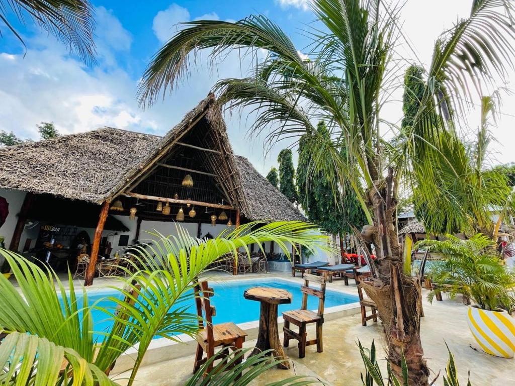 a resort with a swimming pool and palm trees at Babalao Bungalows in Nungwi