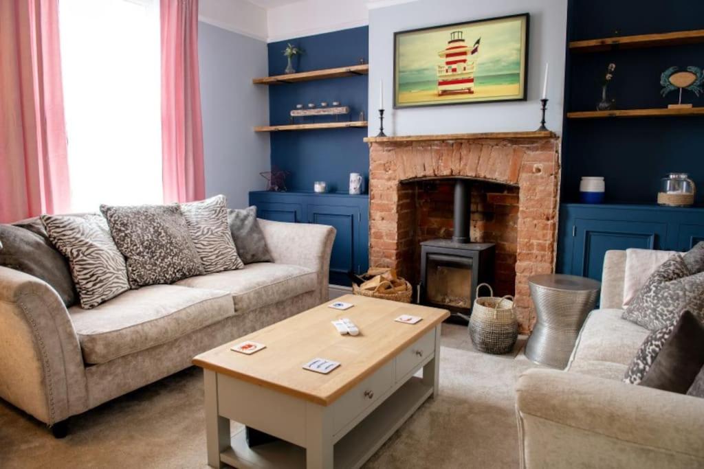 a living room with a couch and a fireplace at Kippers Cottage in Cromer