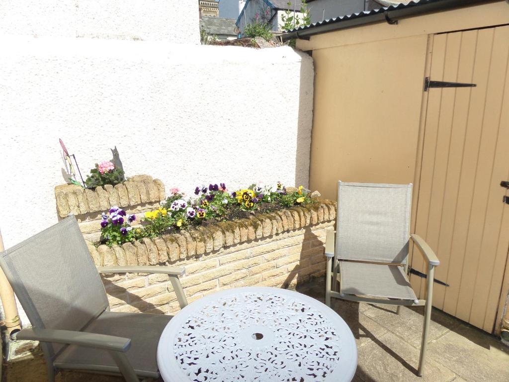 2 chaises et une table sur une terrasse fleurie dans l'établissement Stay Llandudno, à Llandudno