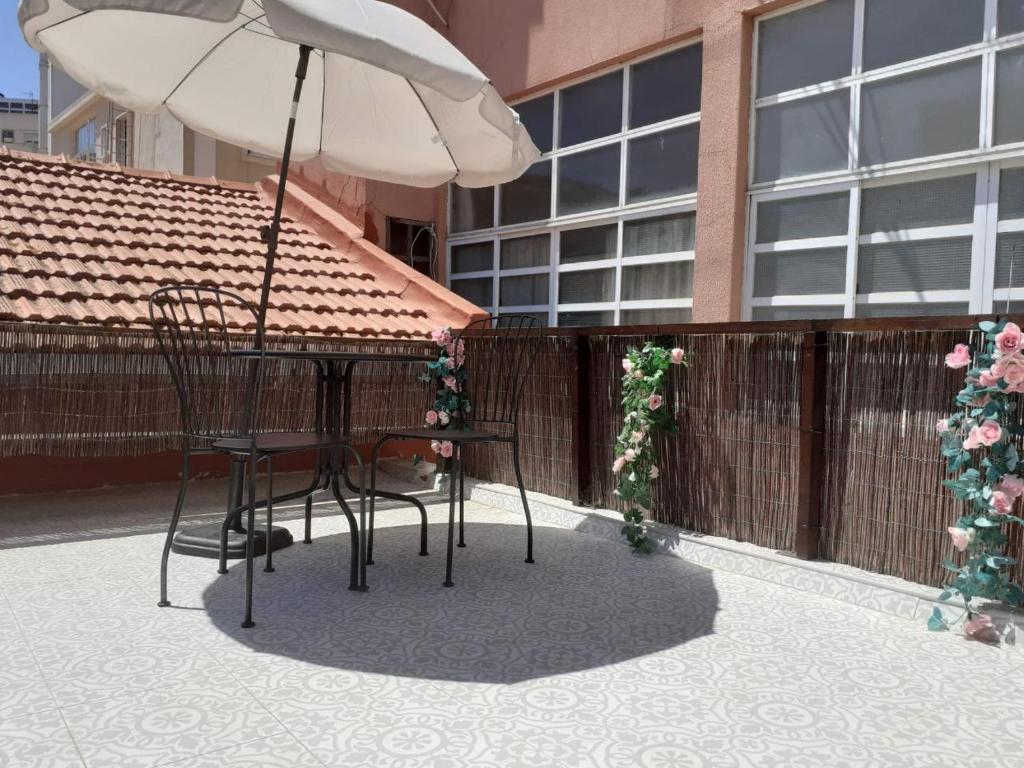 einen Tisch, Stühle und einen Regenschirm auf einer Terrasse in der Unterkunft Moradia em vila da cidade in Lissabon