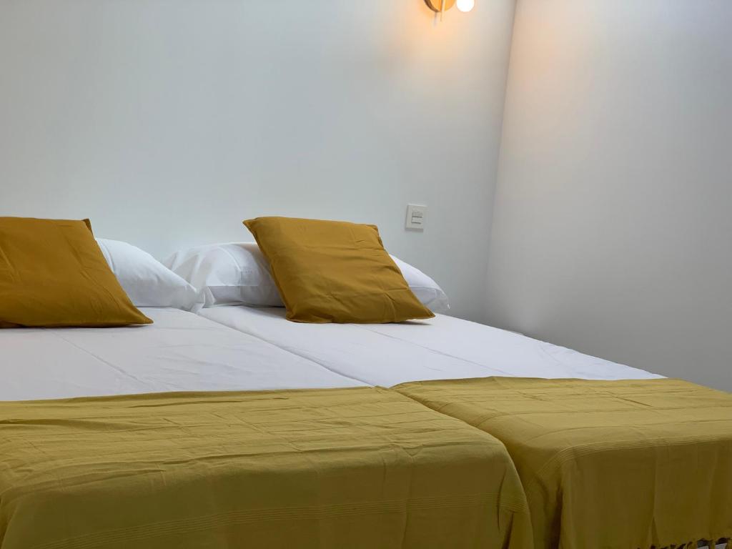 a bedroom with two beds with yellow pillows at Casita Mondoto, encanto en el Pirineo in Frajén