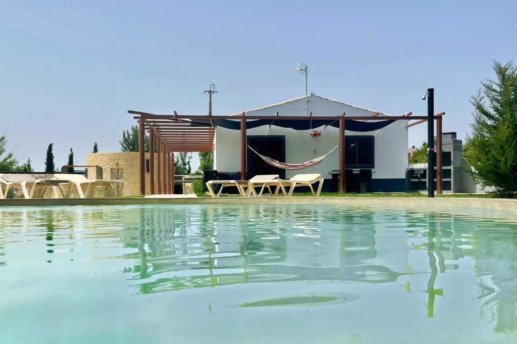 a swimming pool with a hammock and a house at Casa Maria in Moncarapacho