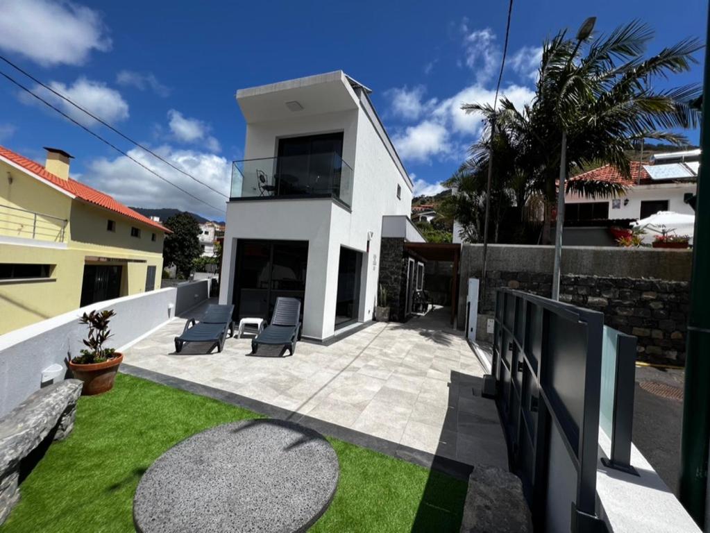 une maison blanche avec 2 chaises sur une terrasse dans l'établissement Casa da Praia, 2min de la PLAGE, hyper centre, à Machico