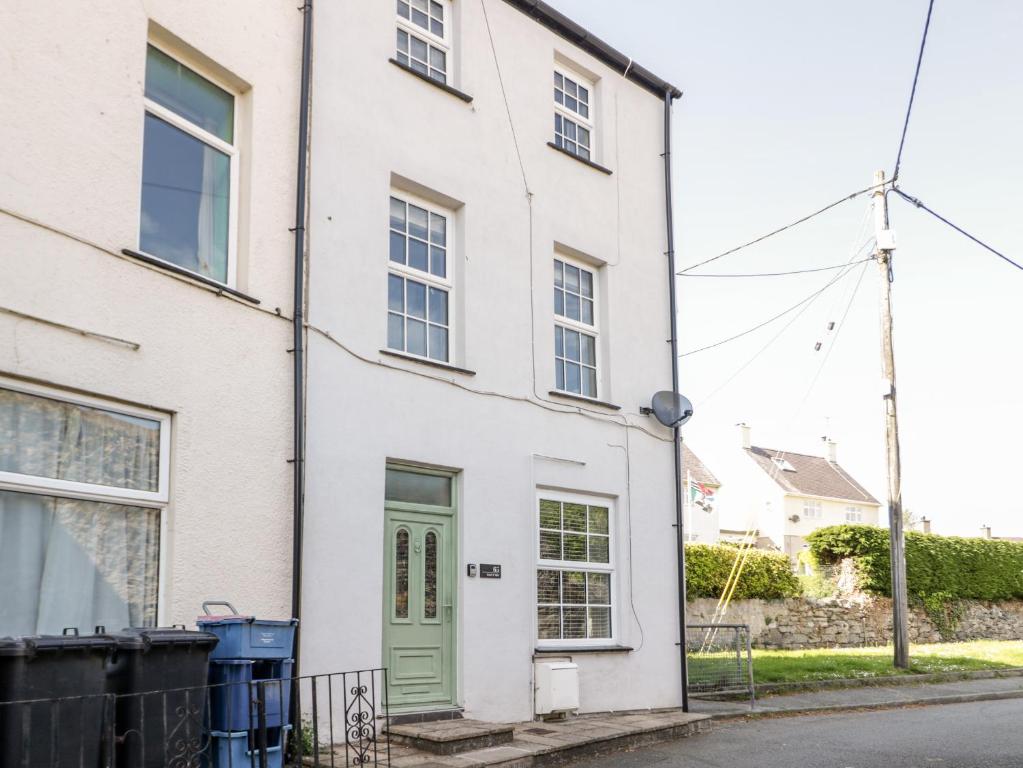 uma casa branca com uma porta verde numa rua em Gwel Y Môr em Beaumaris