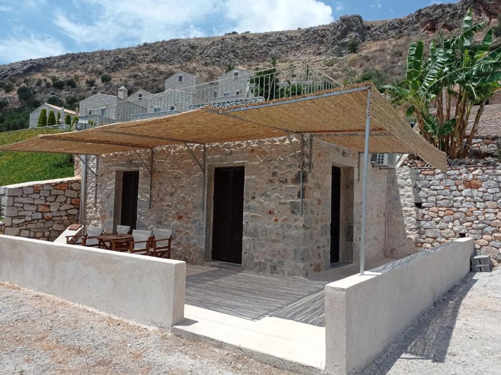 a stone building with a wooden porch with a roof at Mani Blue Thalassa in Oítilon