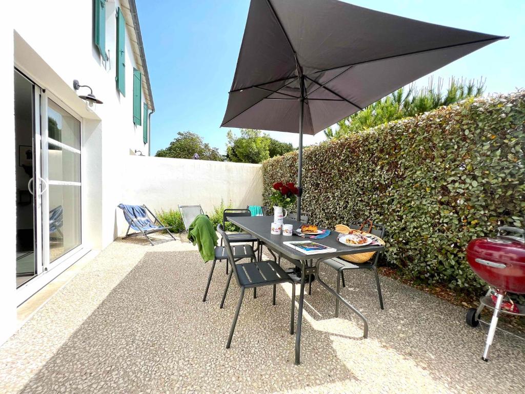 a table and chairs with an umbrella on a patio at Le Clos des Vieux Moulins in La Flotte