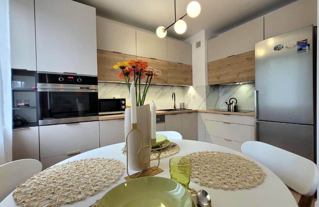 una cucina con tavolo e vaso di fiori di Apartament Arkadia Augustow a Augustów