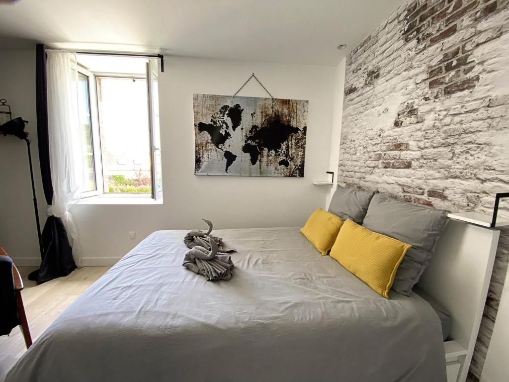 ein Schlafzimmer mit einem Bett mit Ziegelwand in der Unterkunft Le petit atelier - Studio - WIFI - Coeur de ville - Parking in Pont-lʼAbbé